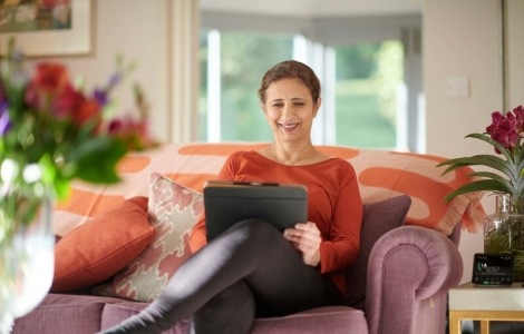 Woman sitting on sofa looking at iPad.