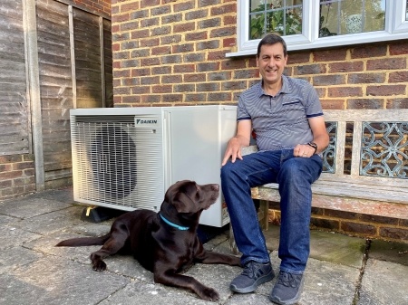 Zero Carbon Home Director, Dan Hopcroft sitting next to Daikin hybrid heat pump 